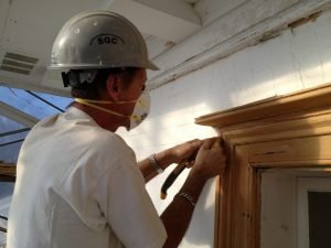 Décapage avec grattoir sur fenêtre de maison du patrimoine